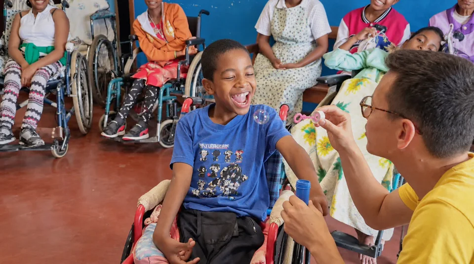 A child in a wheelchair interacting with an adult during a group activity